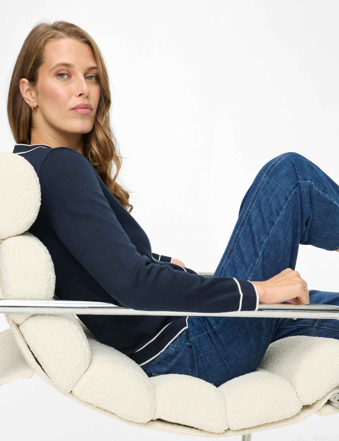 Femme portant un Cardigan boutonné à col contrasté ANN, assise sur une chaise design, allure élégante et détente.