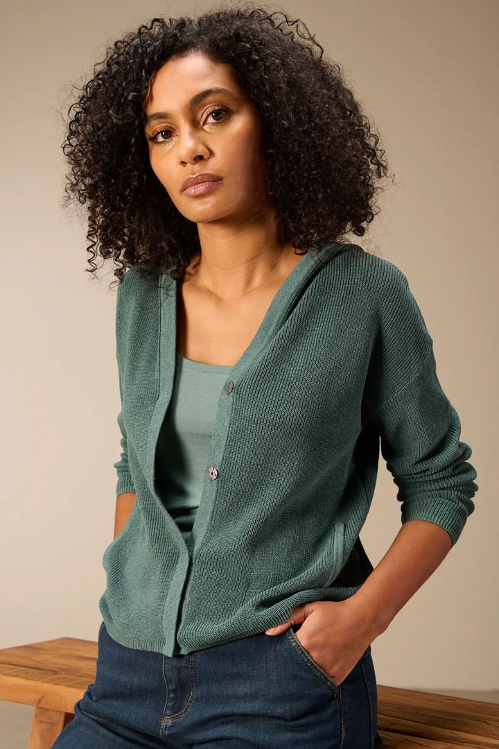 Femme portant un cardigan à capuche en maille vert émeraude, style décontracté avec capuche intégrée et fermeture boutonnée.