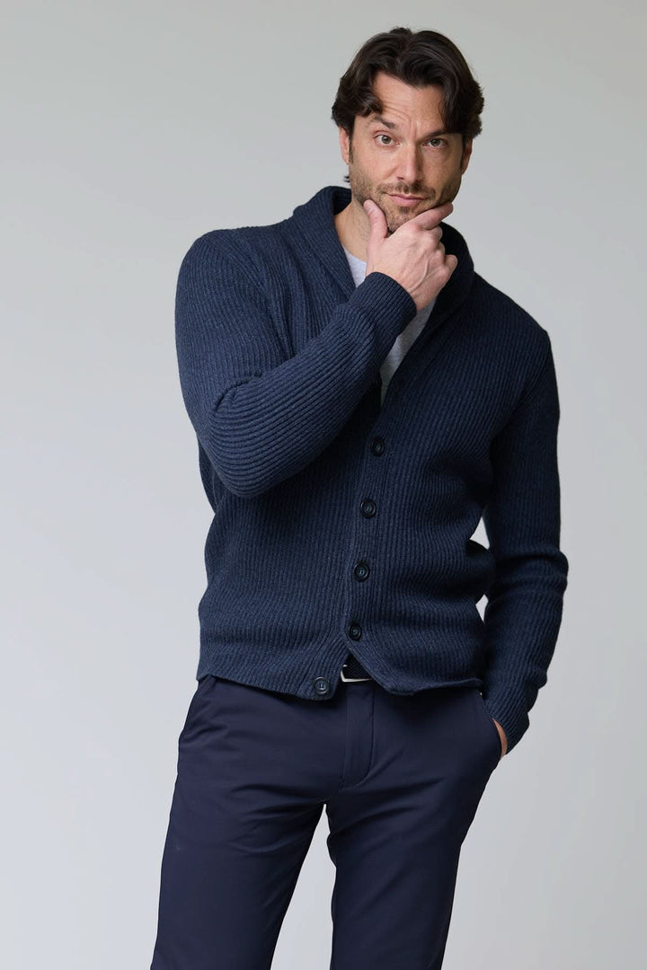 Cardigan à col châle en laine, maille côtelée épaisse, homme posant avec main sur le menton, coupe ajustée, boutonnière devant.
