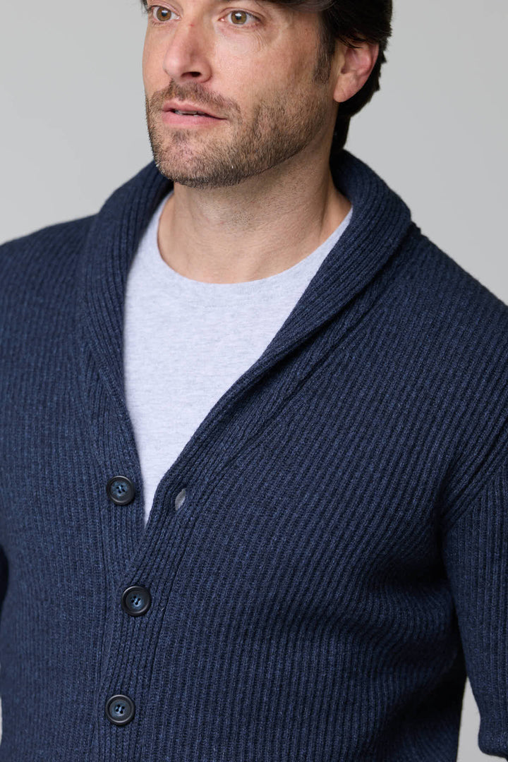 Homme portant un cardigan à col châle en laine bleu foncé, avec maille côtelée et fermeture à boutons, style élégant et confortable.
