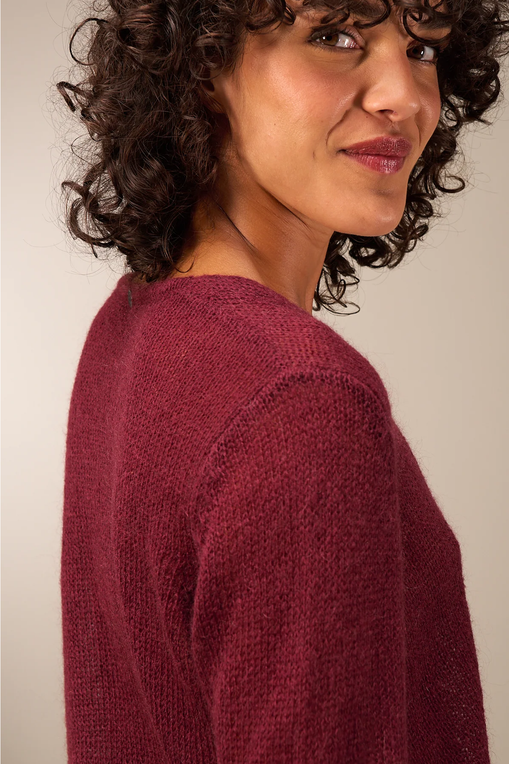 Femme portant un cardigan coupe droite bordeaux avec encolure en V, idéal pour un look élégant et polyvalent. Décris moi le produit.