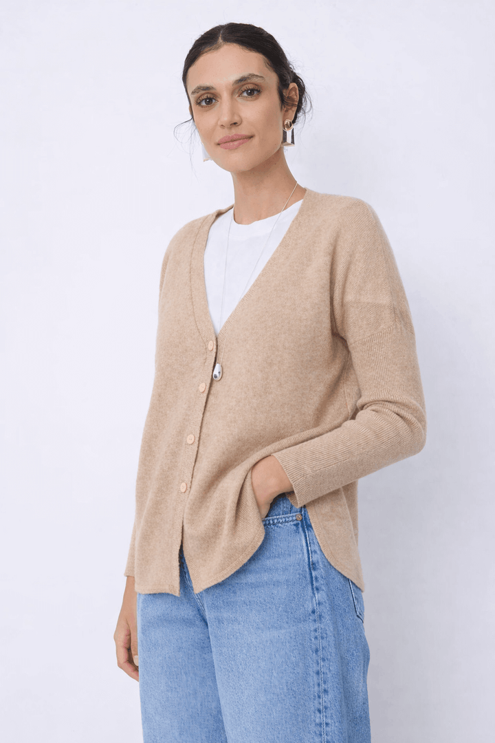 Femme portant le Cardigan en cachemire Alicia beige avec encolure en V et fermeture boutonnée, silhouette épurée pour superpositions confortables.