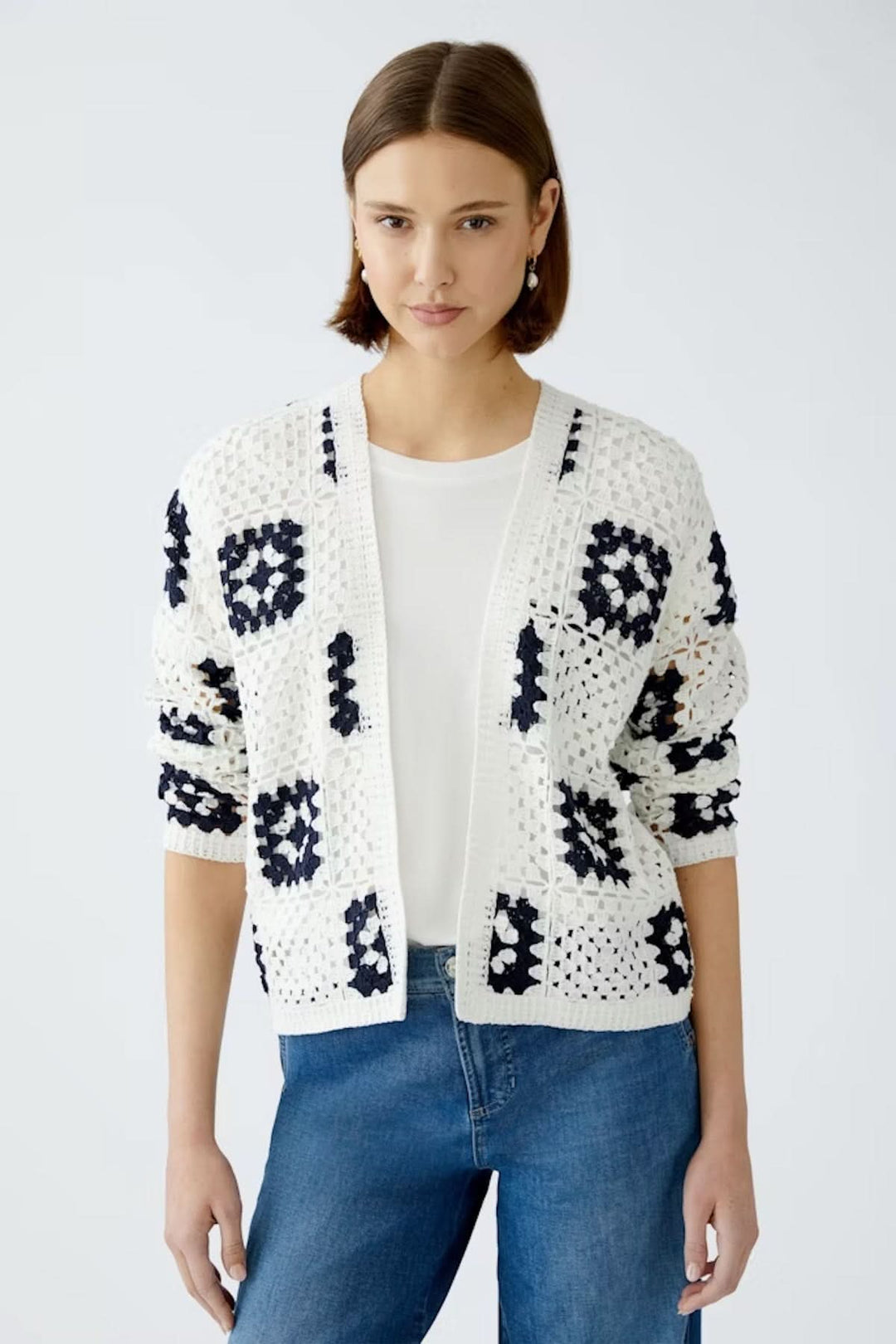Cardigan en crochet blanc avec motifs géométriques marines, porté sur t-shirt et jeans pour un look bohème.