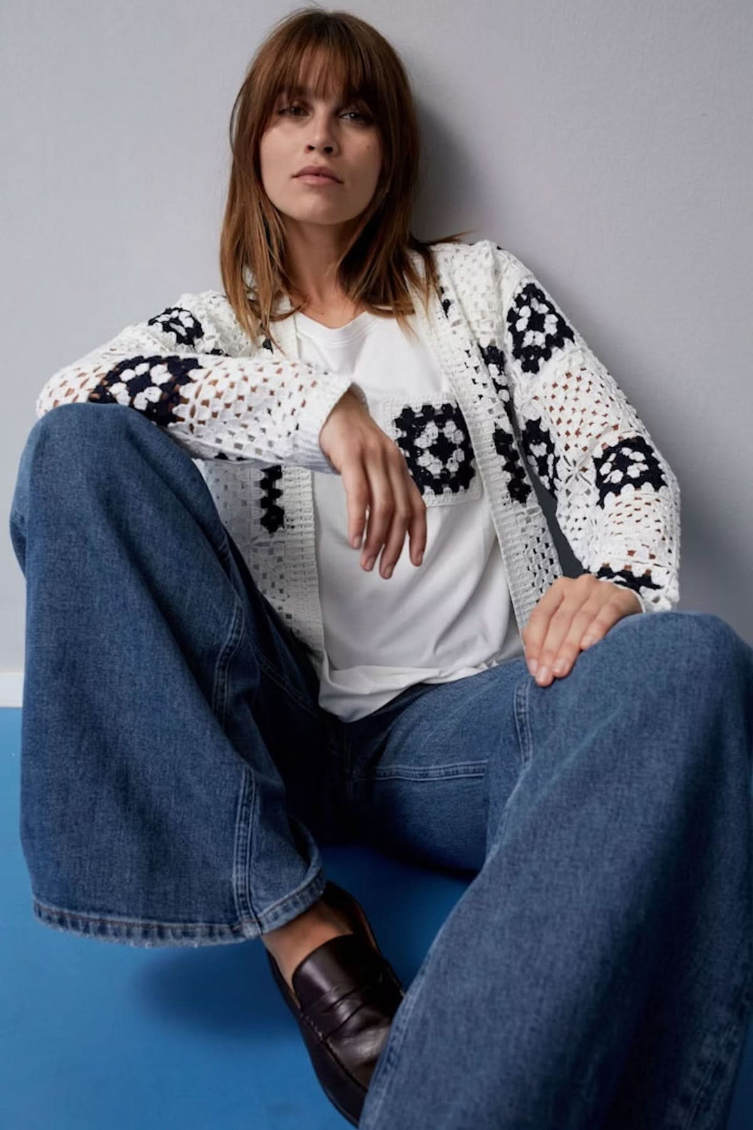 Cardigan en crochet blanc à motifs géométriques marines, porté sur t-shirt blanc et jean bleu, style bohème.