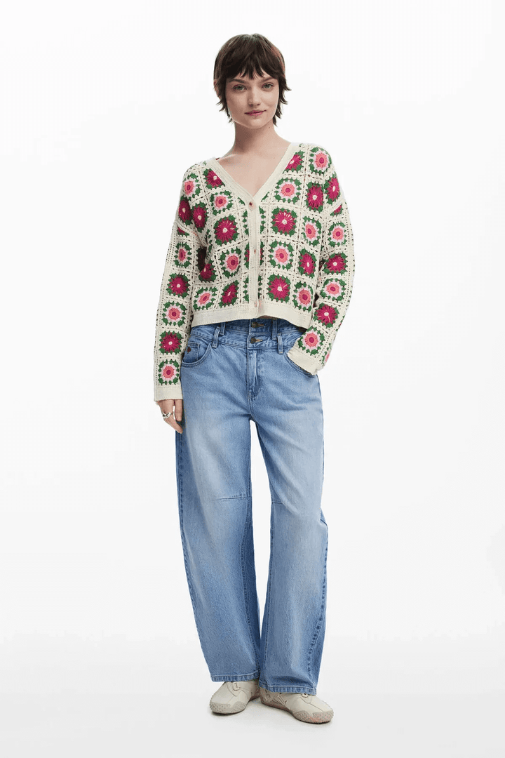 Femme portant un cardigan en crochet à motif floral coloré, col en V, associé à un jean large.
