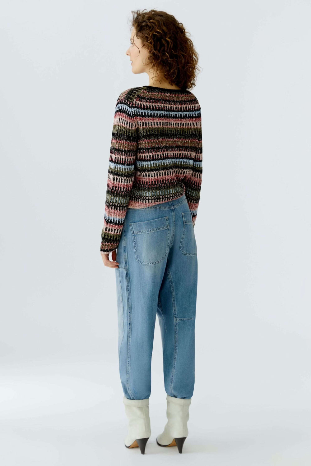 Femme portant un cardigan en maille avec motif graphique et jeans, vue de dos.
