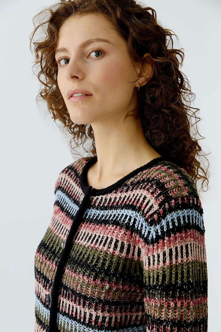 Femme portant un cardigan en maille texturée avec motif graphique multicolore, coupe droite et encolure ronde, mode décontractée.