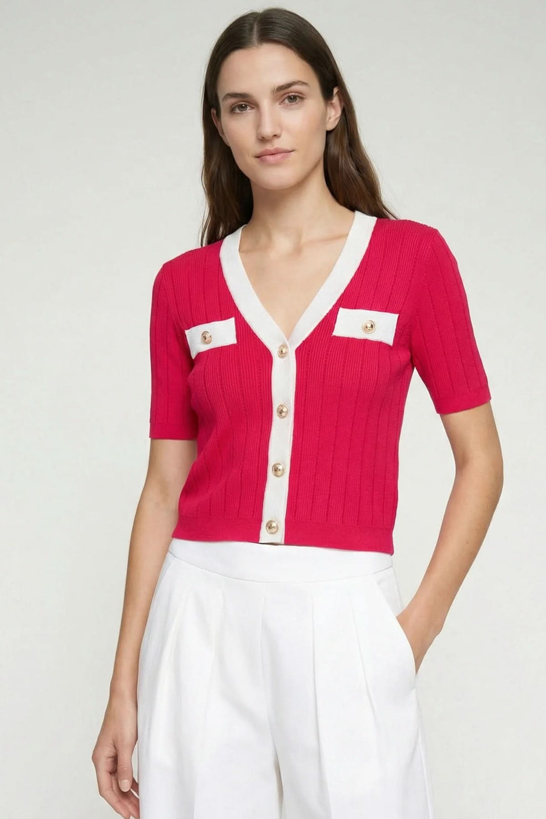 Cardigan en maille à manches courtes rouge avec boutons dorés et détails contrastants, porté par une femme.