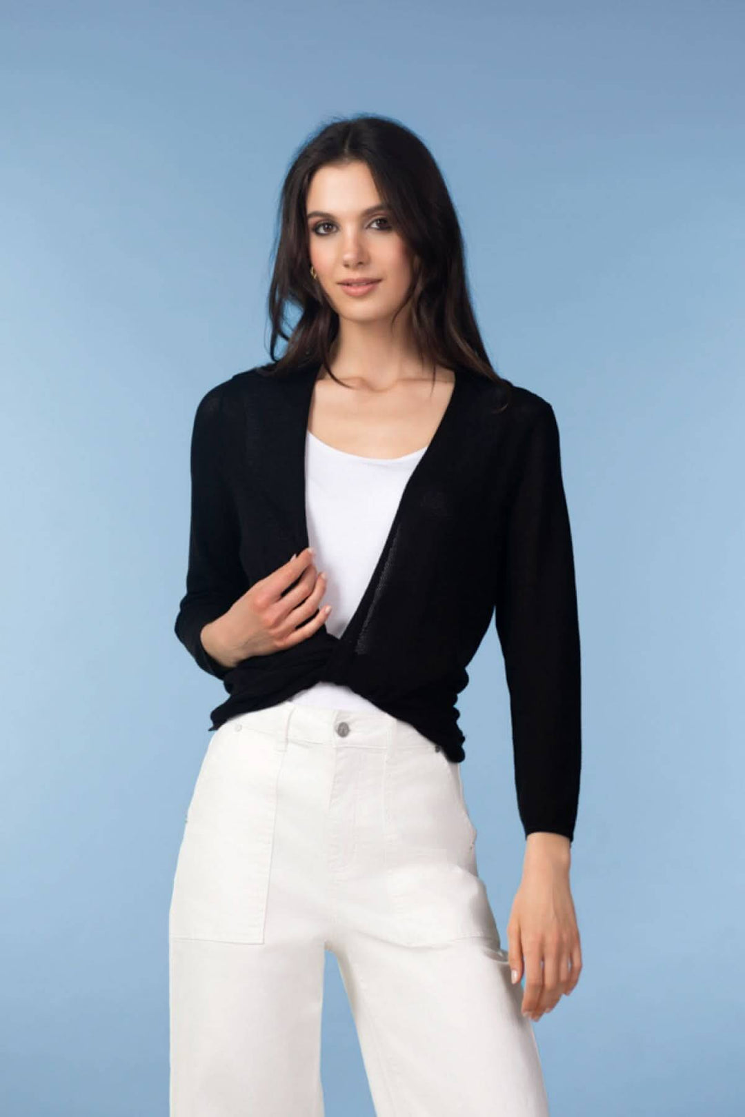 Femme portant un cardigan léger ouvert noir, manches longues, sur un fond bleu.