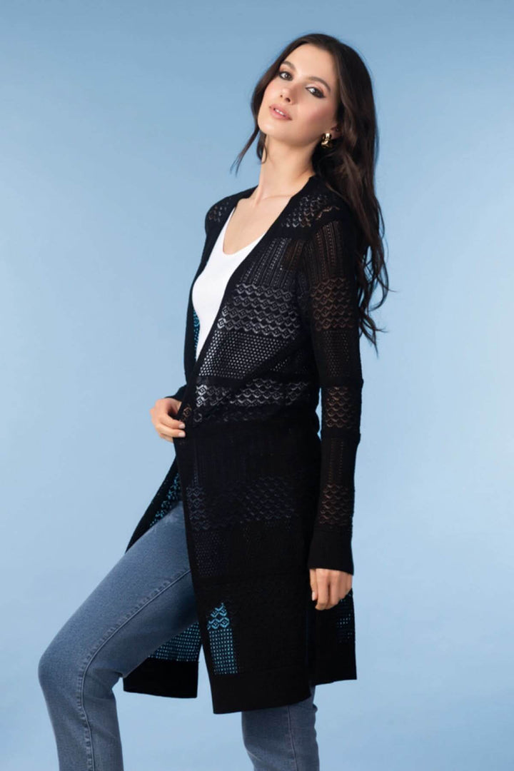 Femme portant un cardigan long en maille ajourée noir avec un jean et un haut blanc, décontracté et élégant, mode raffinée.
