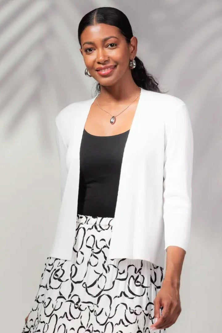 Cardigan à manches 3/4 blanc, ouvert, élégant, porté avec haut noir et jupe imprimée, look minimaliste.