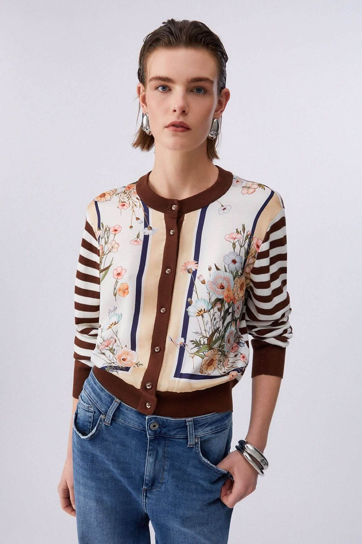 Femme portant un cardigan à manches longues avec motifs contrastés, rayures et motifs floraux, parfait pour un look moderne et élégant.