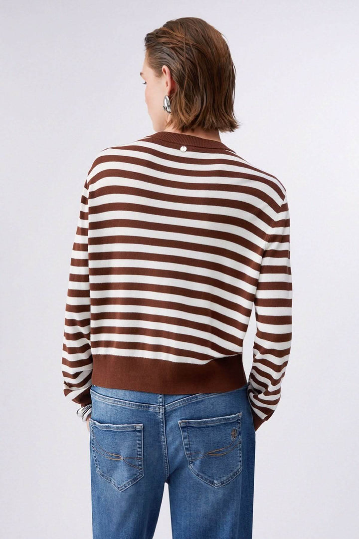 Vue arrière du cardigan à manches longues avec motifs contrastés, rayures marron et blanches, porté avec un jean décontracté.