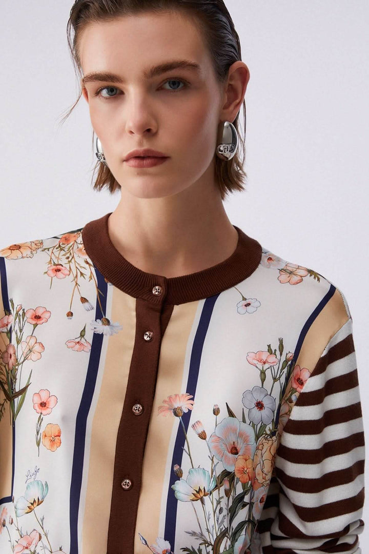 Cardigan à manches longues avec motifs contrastés porté par une femme, avec rayures et motifs floraux, élégant et doux.
