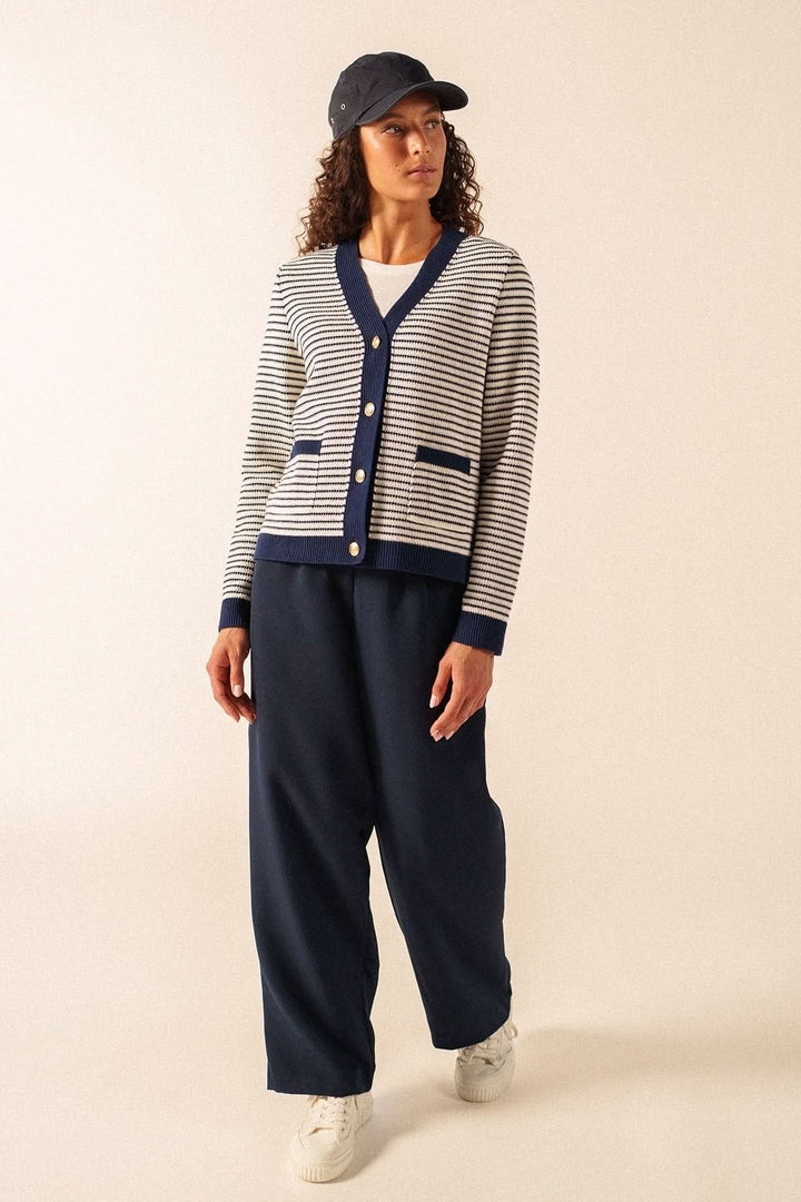 Cardigan rayé style marin ISTRES porté avec un pantalon bleu foncé et une casquette, mettant en valeur une tenue décontractée et moderne.