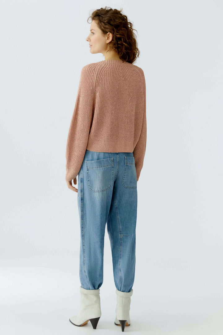 Cardigan tricoté élégant avec encolure en V, coupe courte, porté par une femme de dos, idéal pour superposer ou porter seul.