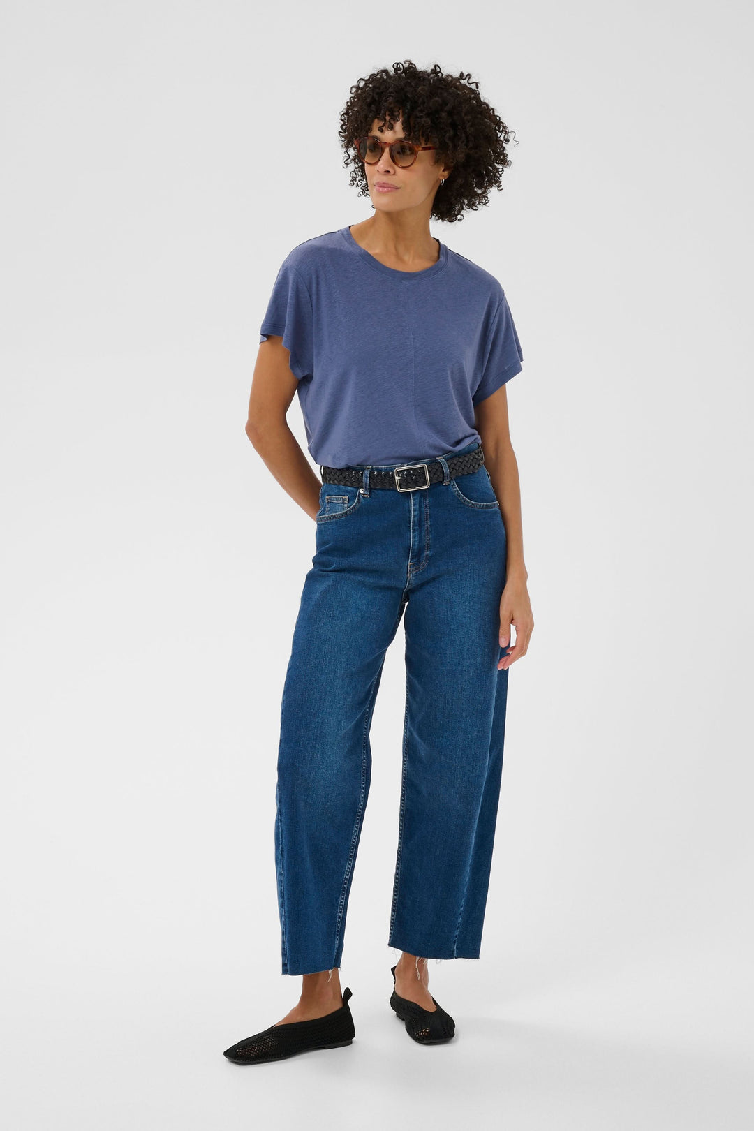 Femme portant le Chandail Anemona bleu avec jean et chaussures noires, illustrant le style minimaliste et contemporain du vêtement.