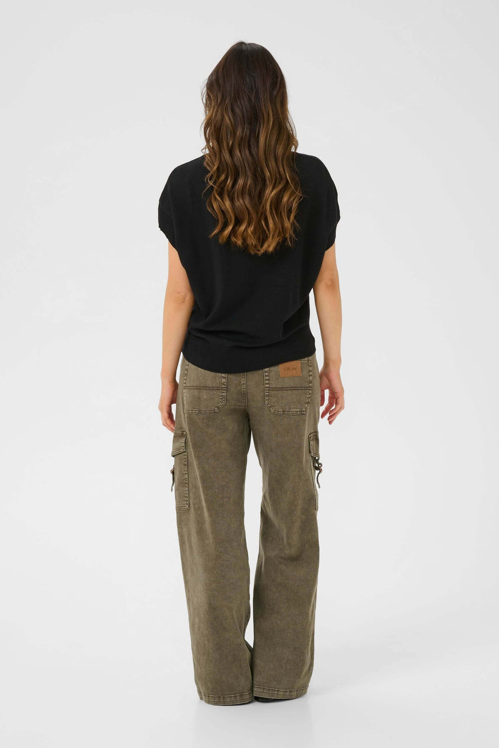 Femme vue de dos portant un chandail noir et un pantalon cargo ample, style décontracté.