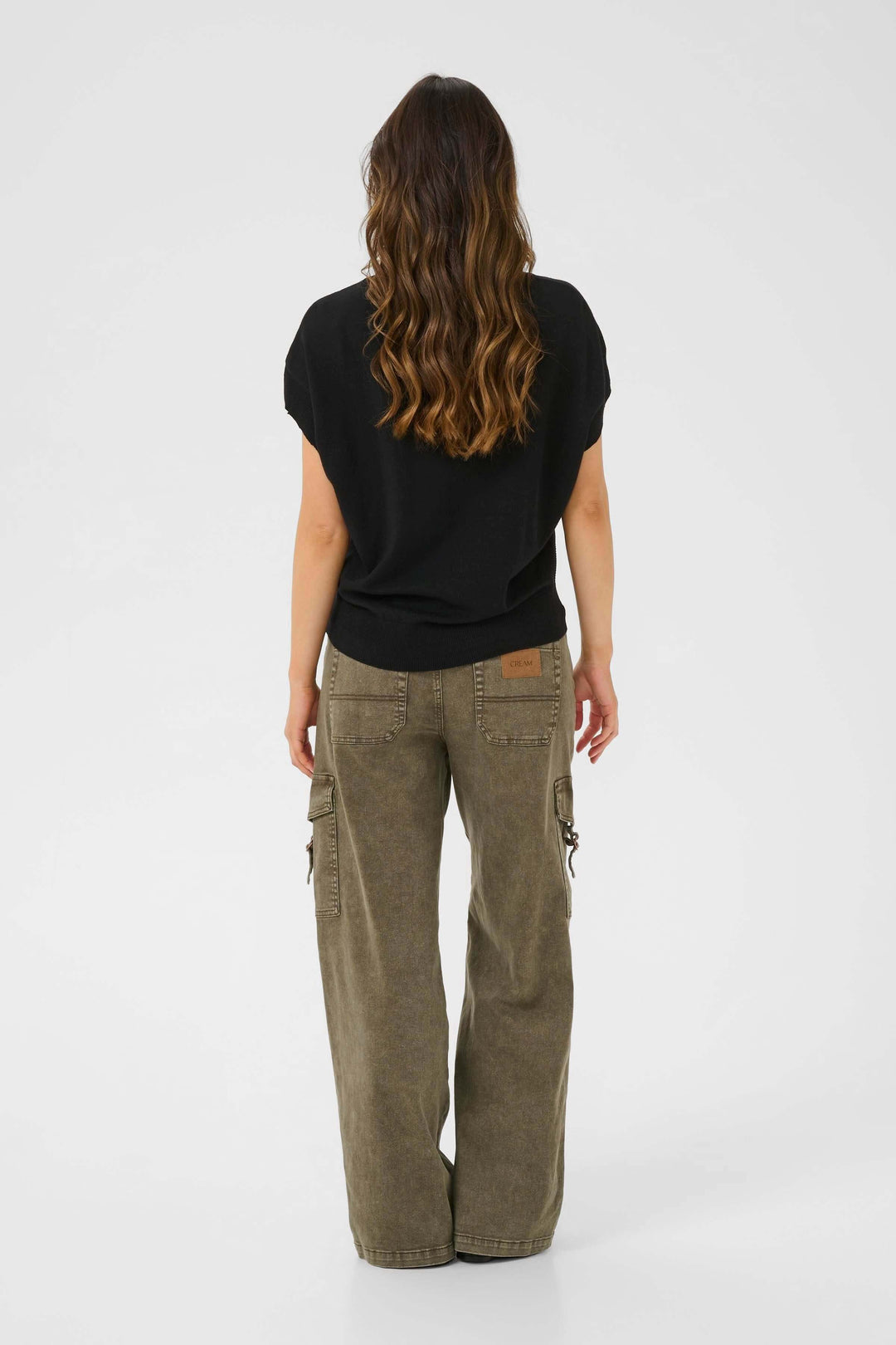 Femme vue de dos portant un chandail noir et un pantalon cargo ample, style décontracté.
