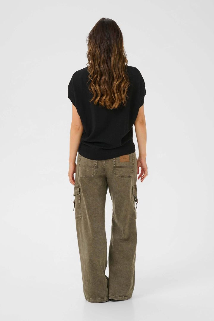 Femme vue de dos portant un chandail noir et un pantalon cargo ample, style décontracté.