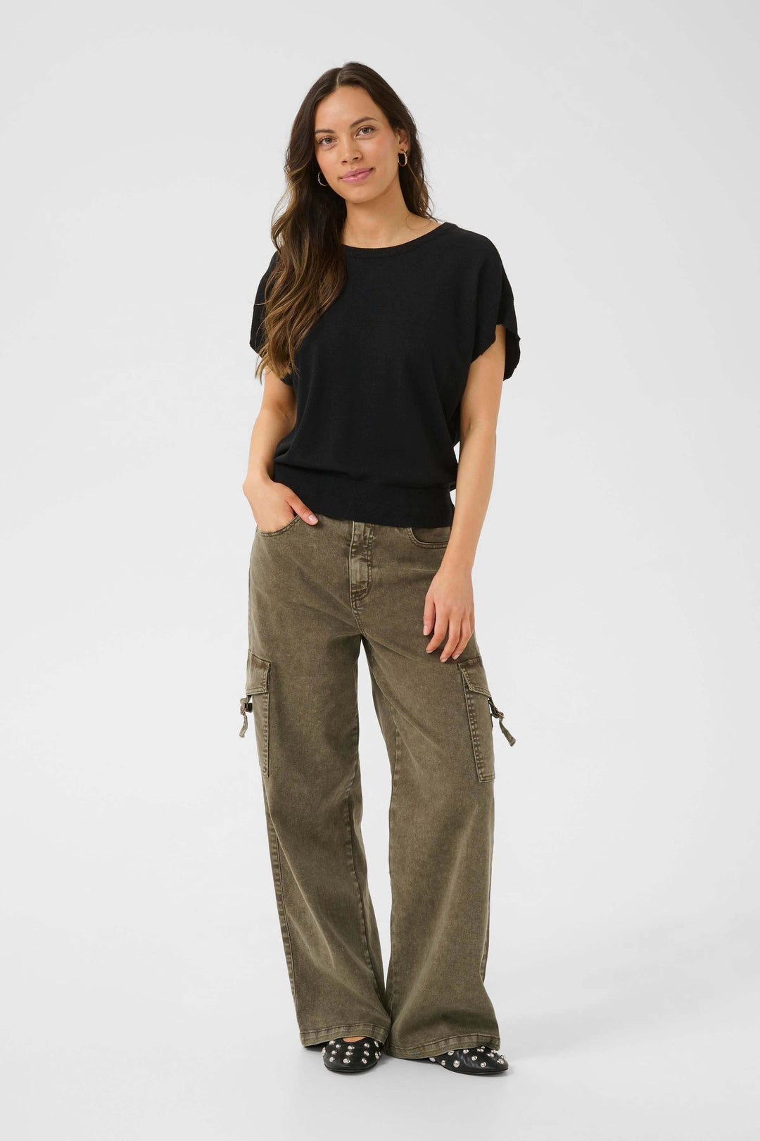 Femme portant un chandail noir décontracté et un pantalon cargo vert, style mode casual.
