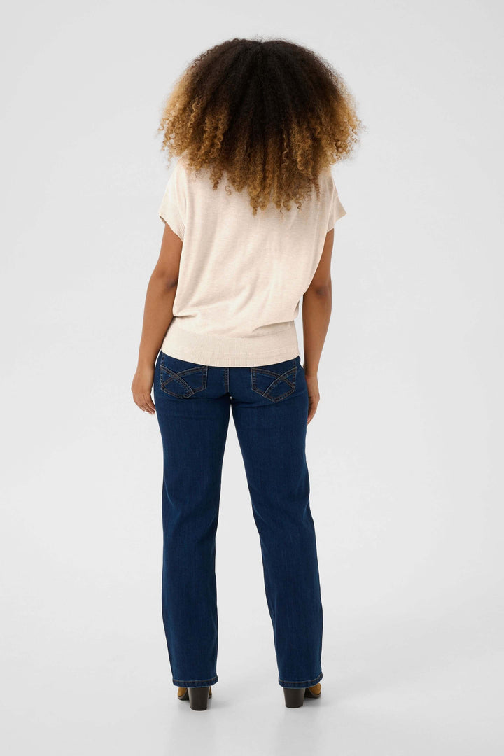 Femme vue de dos portant un chandail beige et un jean bleu, avec cheveux afro crépus.