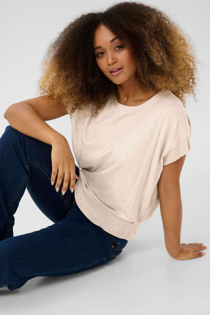 Chandail sans manches beige, coupe ample, style décontracté, porté avec un pantalon en denim.
