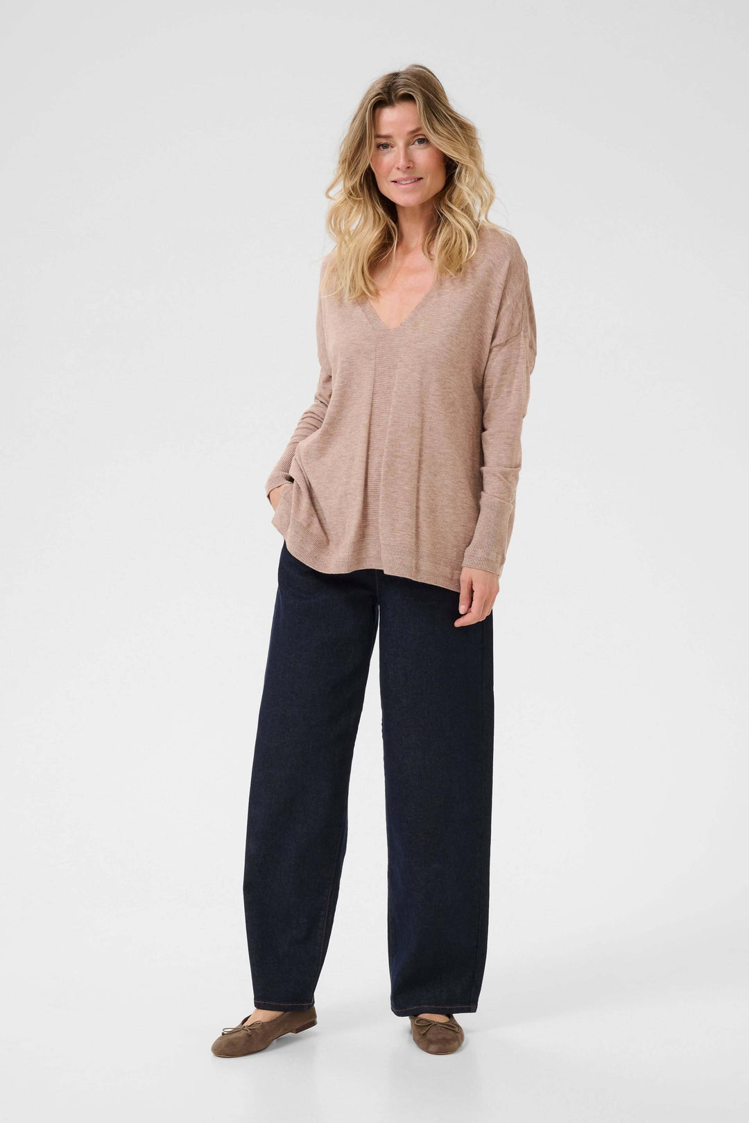 Chandail Dela à col en V, ample et cosy, porté avec un pantalon noir, parfait pour un look décontracté et élégant.