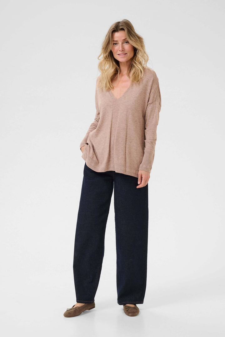 Chandail Dela à col en V, ample et cosy, porté avec un pantalon noir, parfait pour un look décontracté et élégant.