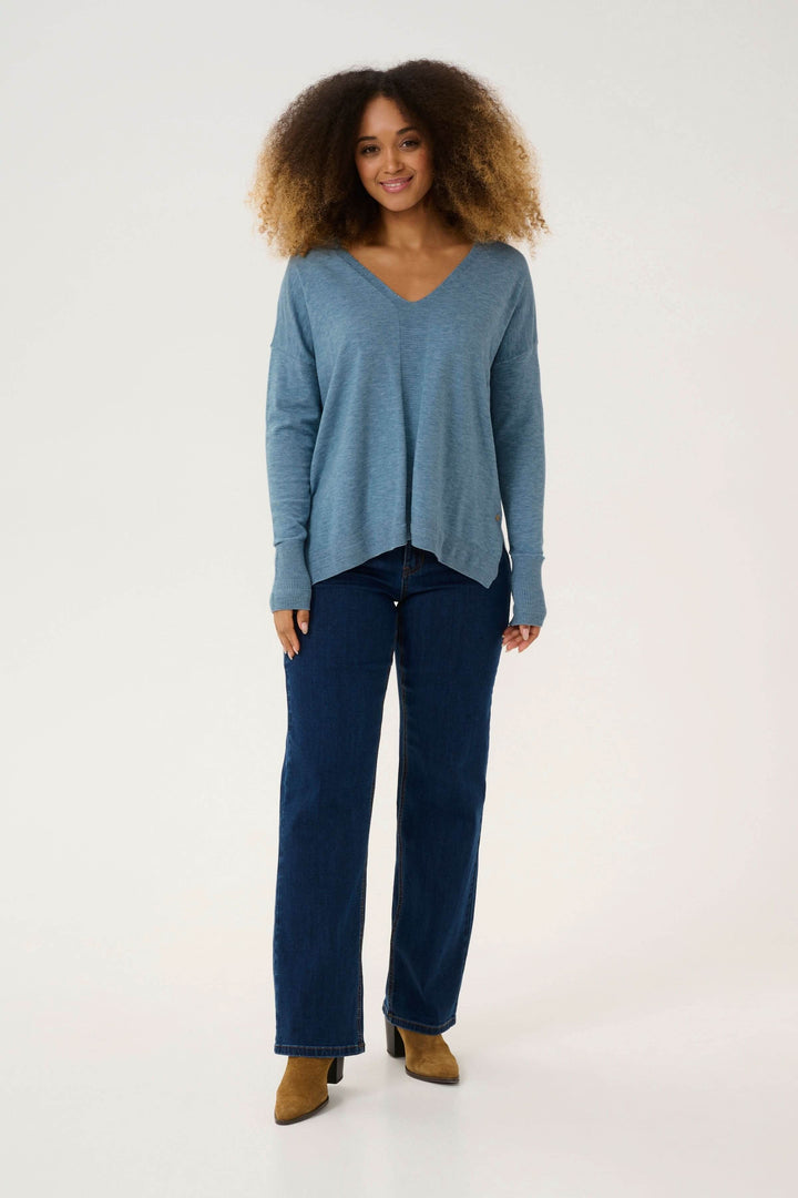 Femme portant un chandail Dela décontracté à col en V, associé à un jean, pour un style cosy et élégant.
