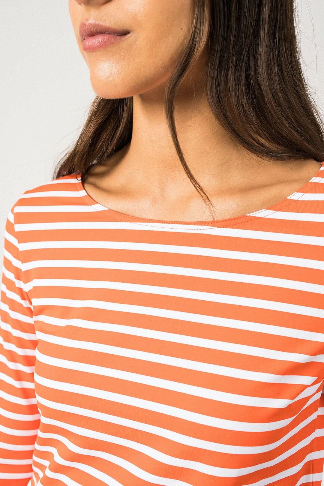 Close-up of a woman wearing a striped orange and white top with a round neckline, showcasing sporty elegance.