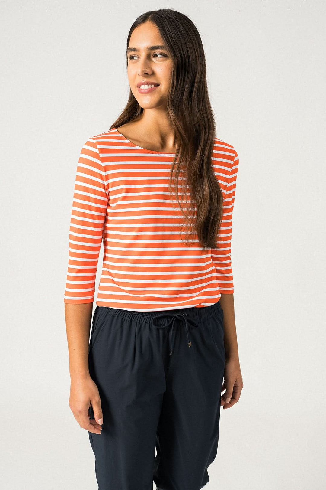 Femme en chandail rayé orange et blanc à manches 3/4, coupe ajustée, style marin, tenue décontractée.