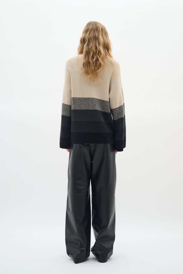 Chandail Gittel à col montant, rayures horizontales modernes, porté avec un pantalon ample, style élégant et cosy.