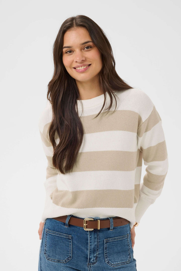Femme portant le Chandail Harriet en tricot à rayures horizontales, coupe confortable, avec ceinture marron et jean décontracté.