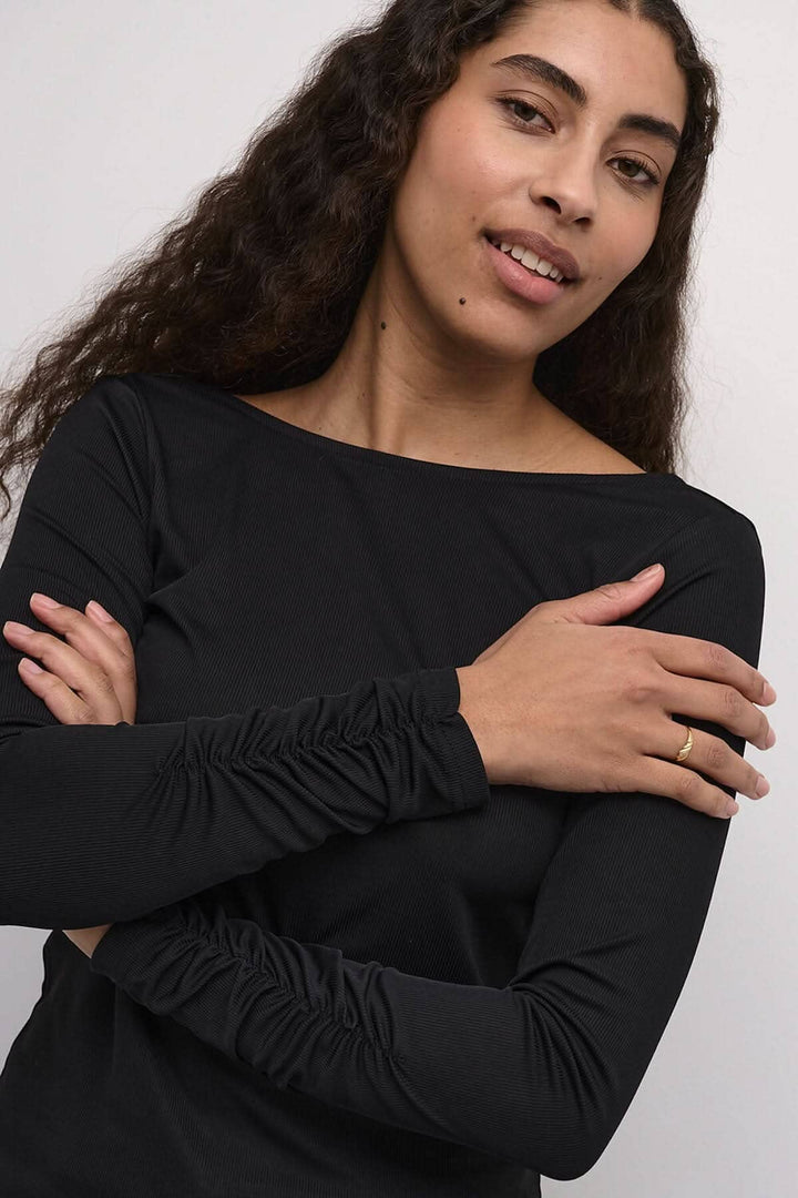 Chandail Kaffe noir à manches longues avec détails élégants et dos dégagé, modèle féminin portant le vêtement.