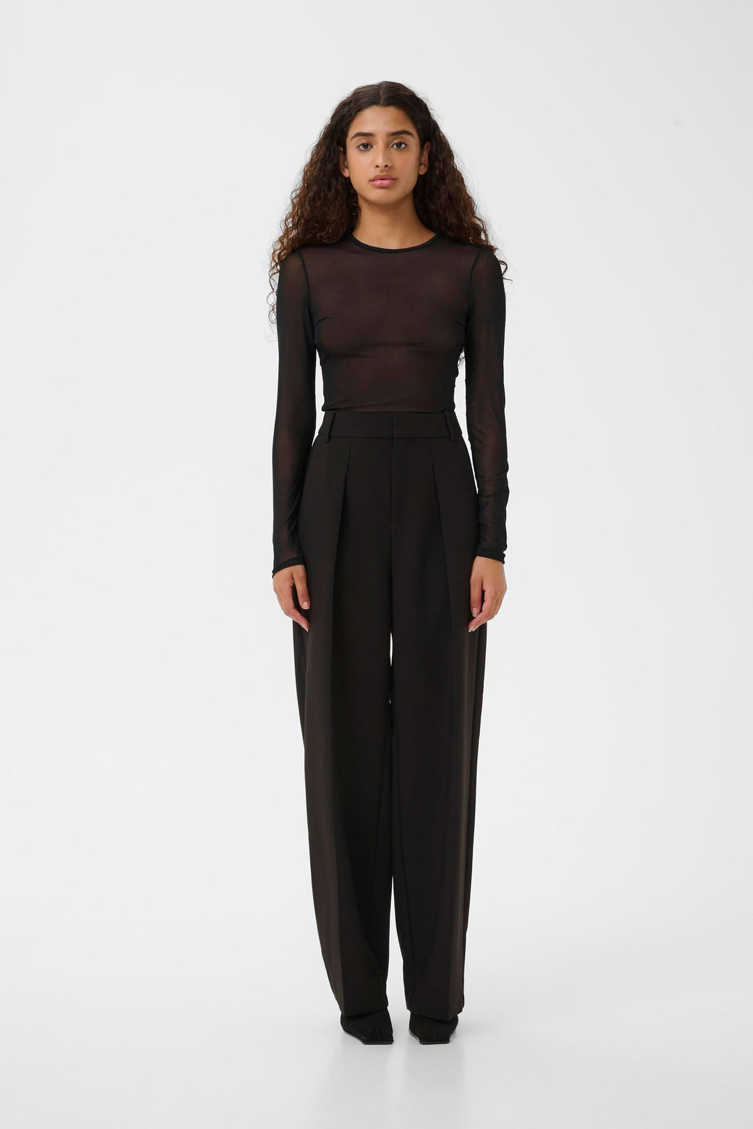 Modèle portant le Chandail Kaia en tulle transparent à manches longues, style moderne et ajusté pour une allure sophistiquée et contemporaine.