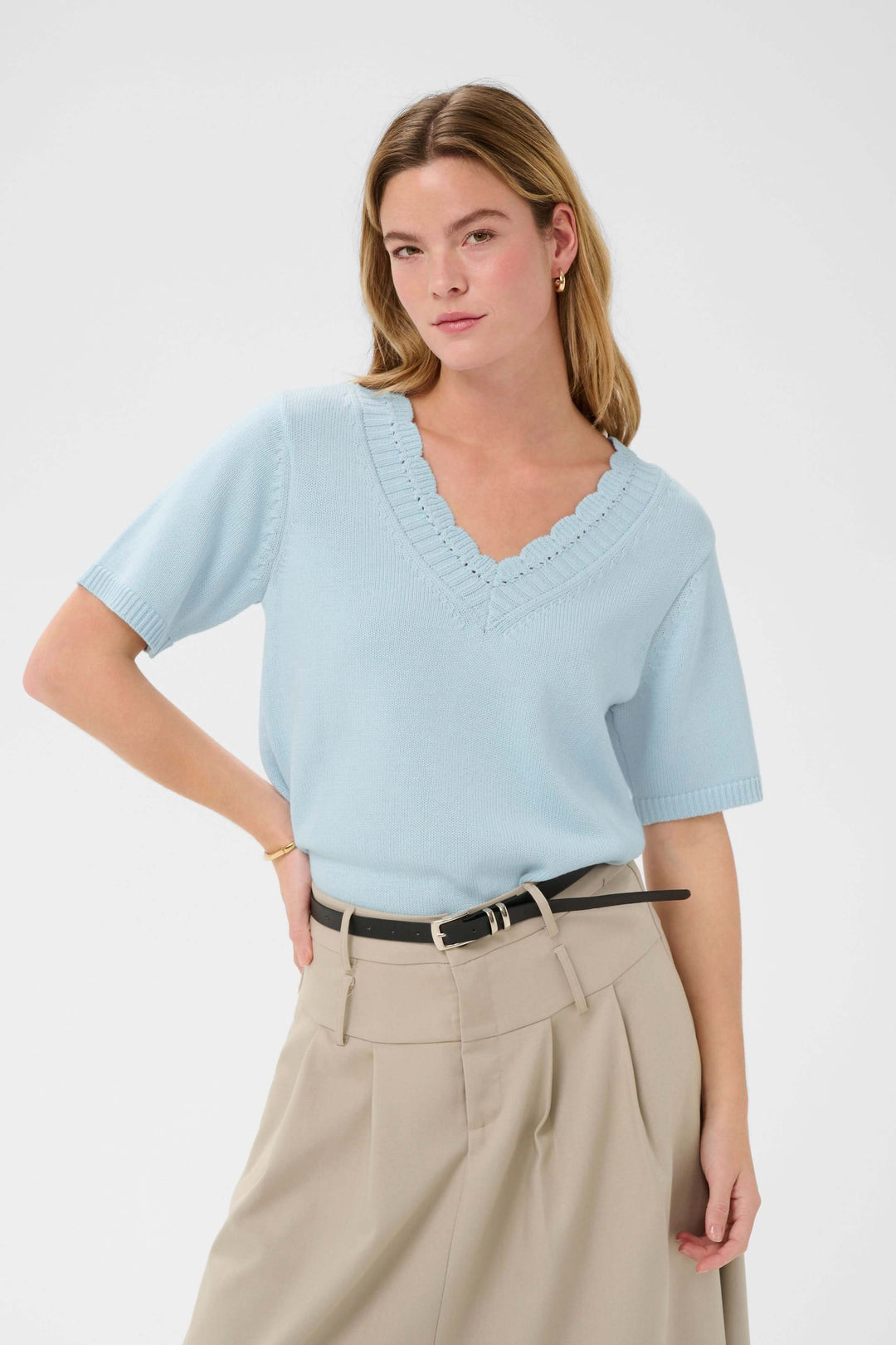 Femme portant le Chandail Liliana en tricot à col en V festonné, manches courtes, tricot fin et léger, couleur bleu ciel.