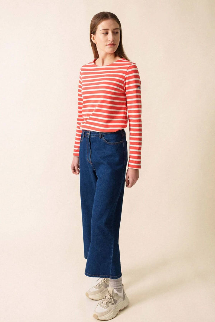 Femme portant un chandail rayé rouge et blanc avec un jean bleu, mode féminine chic et décontractée.