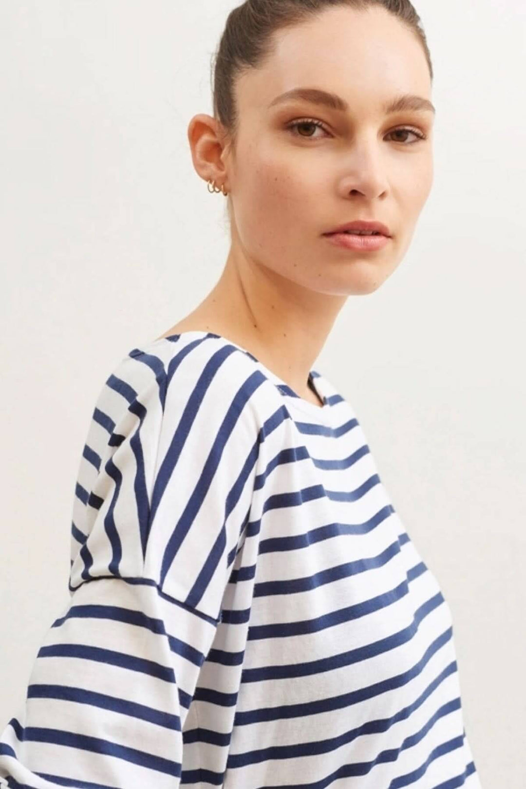 Femme portant un chandail rayé bleu et blanc, moderne et décontracté, style marinière Minquiers Drop.
