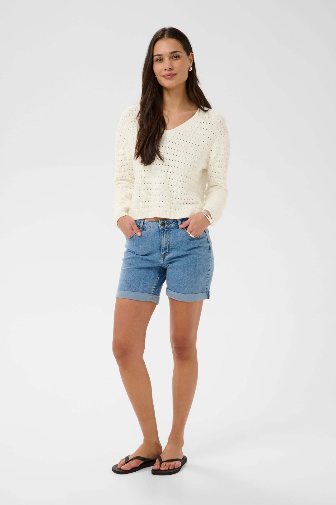 Femme portant un Chandail Metta en maille ajourée avec encolure en V, style décontracté et féminin.