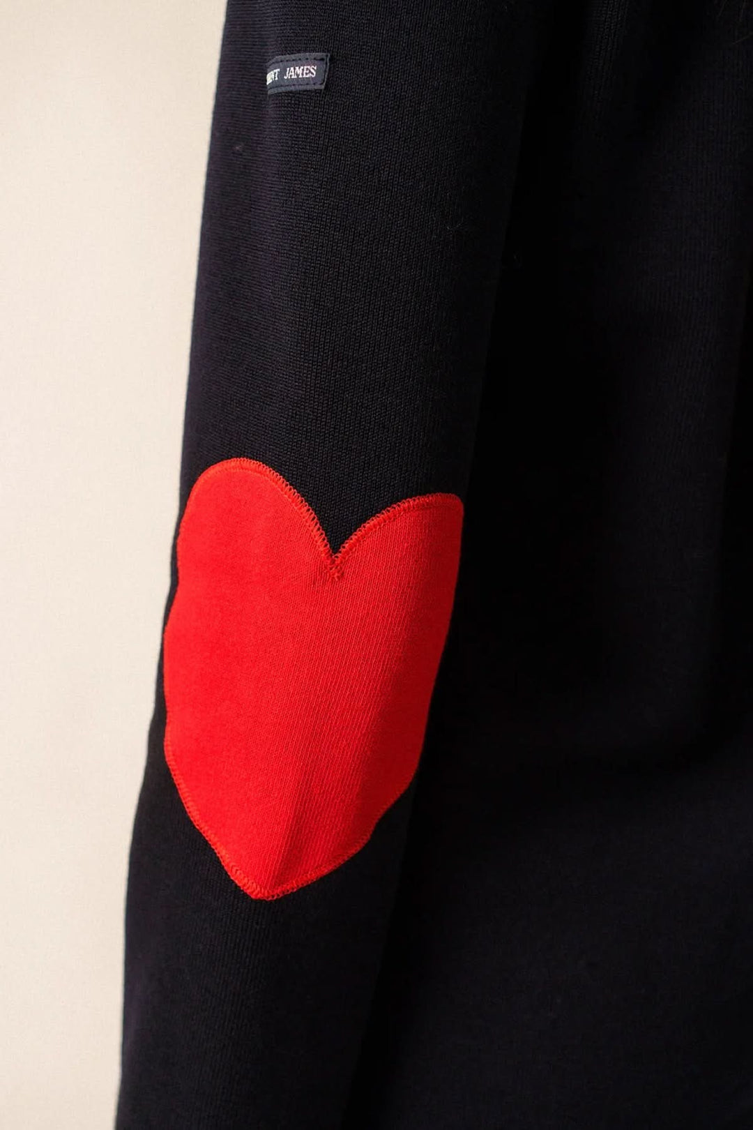 Chandail Vaujany noir avec patch cœur rouge sur la manche, alliant confort et style moderne.