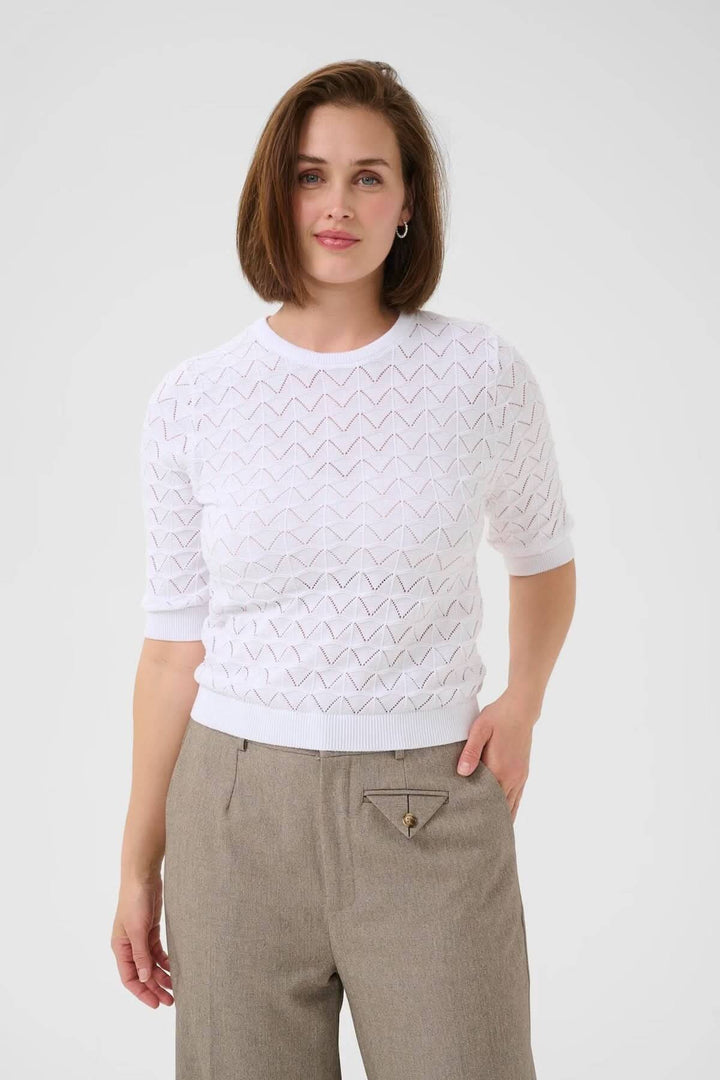 Chandail ajouré blanc avec motif graphique, manches courtes et col rond, parfait pour un look chic.
