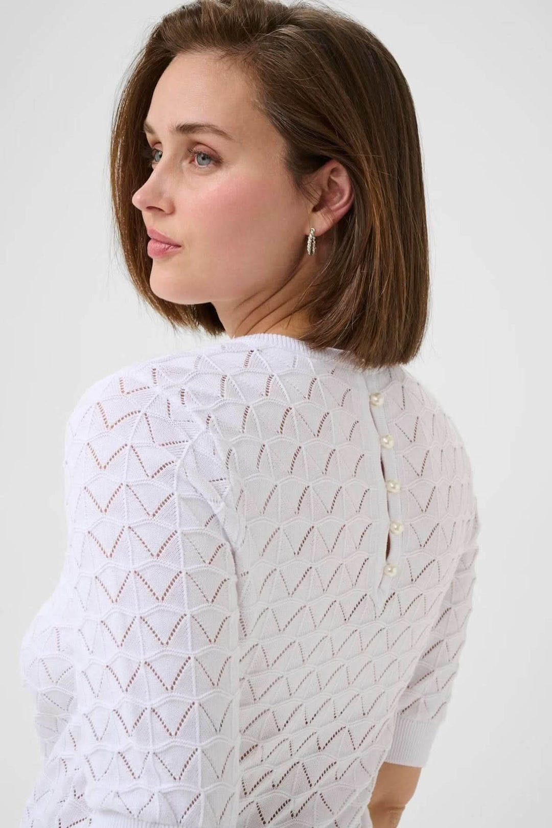 Chandail ajouré blanc avec motif géométrique et détails de perles au dos, élégant et féminin.