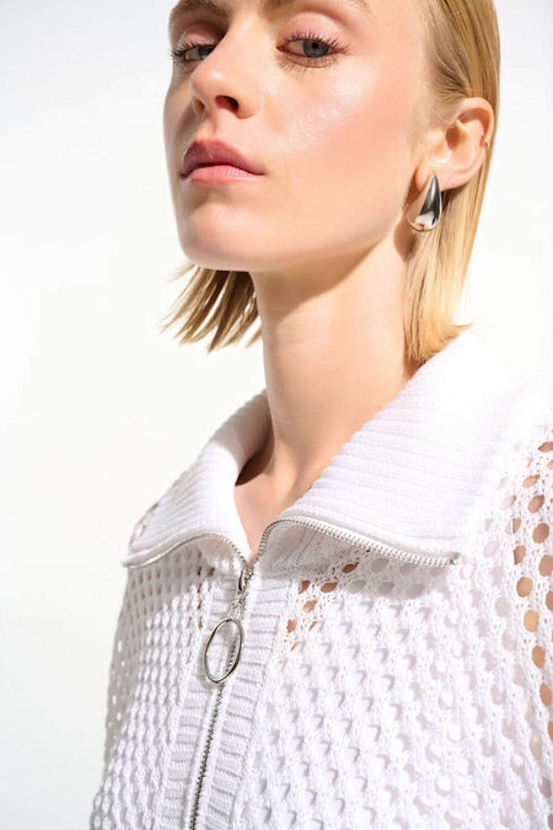 Chandail ajouré à col zippé blanc, maille ouverte et col montant, vue de près sur modèle, éclat moderne et élégant.