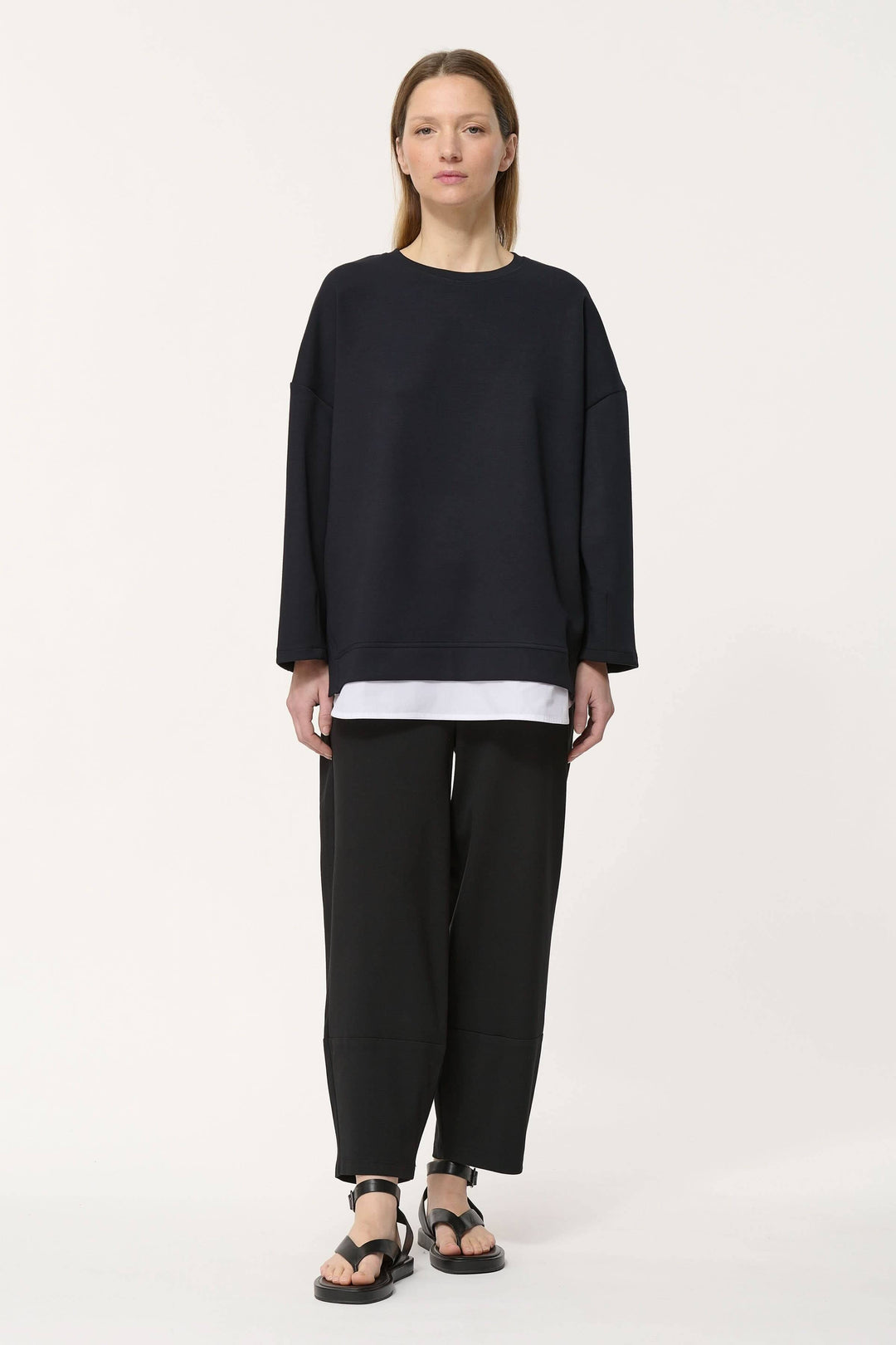 Chandail ample noir avec superposition blanche, look minimaliste, idéal pour une tenue confortable.