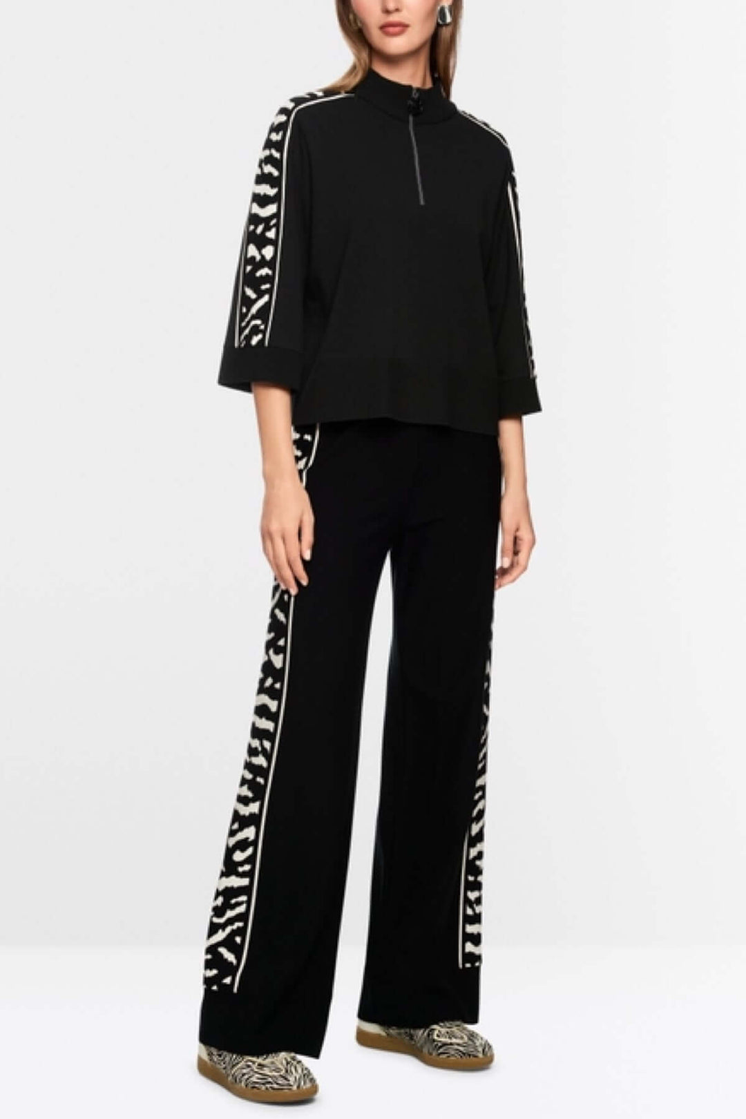 Chandail ample noir avec manches 3/4 et motif animalier, col avec fermeture éclair, et label de durabilité Rethink Together.