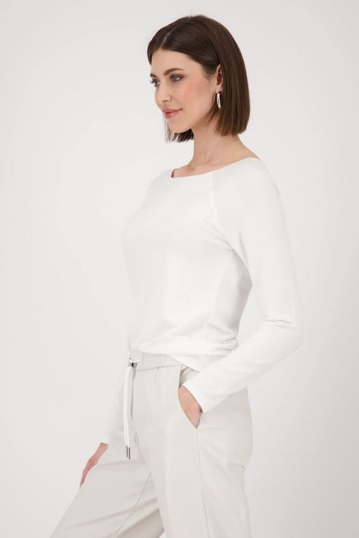 Chandail basique à manches longues, col rond, coupe cintrée, porté avec un pantalon élégant.