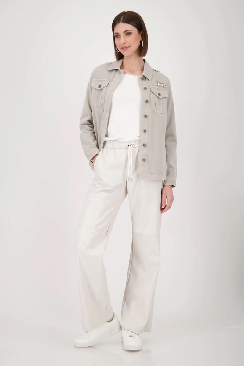 Femme portant un chandail basique à manches longues, en jean, avec un pantalon blanc élégant.