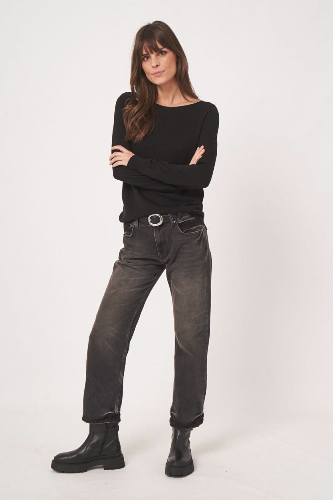 Femme portant un chandail basique à encolure bateau et un jean noir, affichant un look minimaliste et élégant.