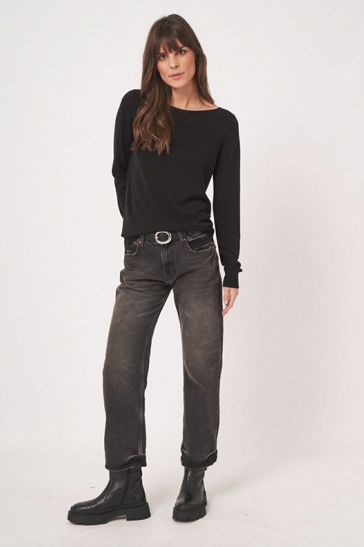Chandail basique à encolure bateau, porté avec un jean noir pour un look décontracté et élégant.